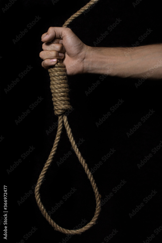 Hand holds a noose on a black background. Social problem. The end of the path Hand holds a noose on a black background. Social problem. The end of the path