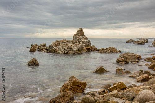 roca en forma de isla muy cerca de la orilla del mar con cielo cargado