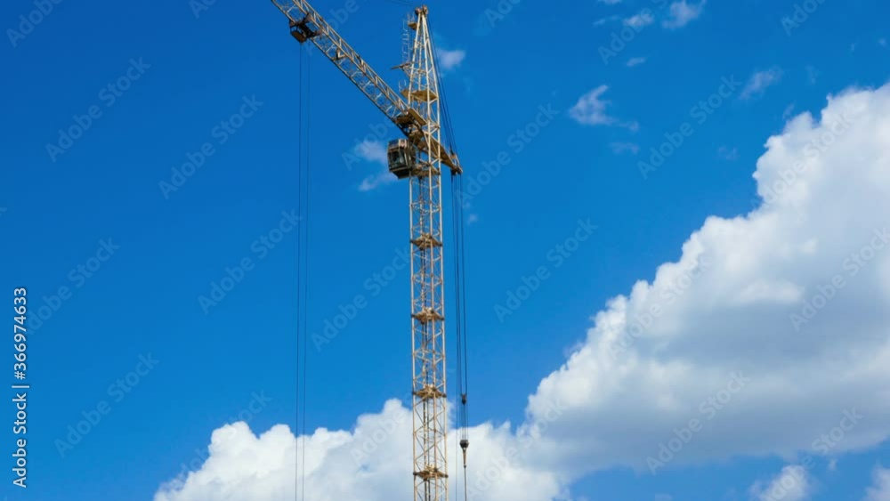 The work of a construction crane against the background of the cloudy sky time laps. Construction site process working time laps The work of a construction crane against the background of the cloudy sky time laps. Construction site process working time laps
