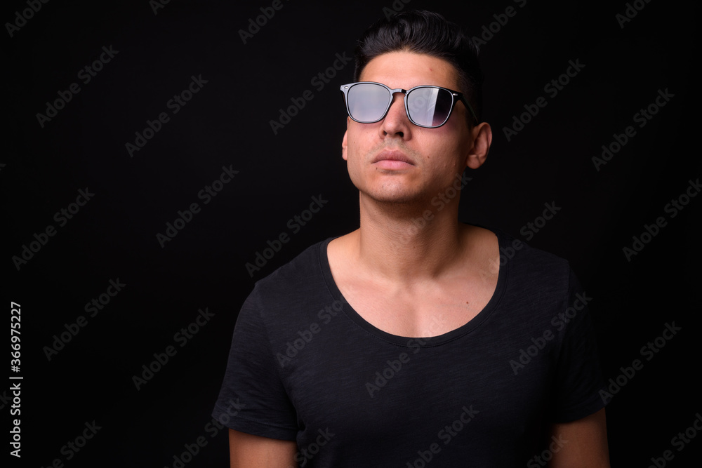 Young handsome multi ethnic man against black background Young handsome multi ethnic man against black background