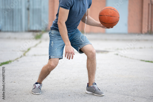Man plays basketball in the street yard during the day