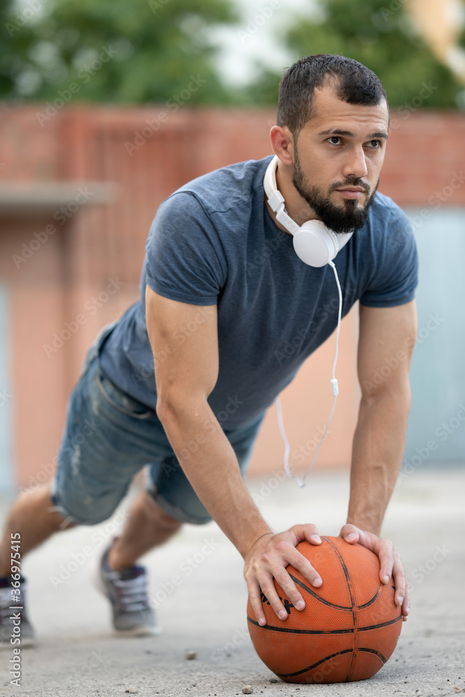 © Vladimir - Man on the street is doing push-UPS, leaning on a basketball © Vladimir - Man on the street is doing push-UPS, leaning on a basketball
