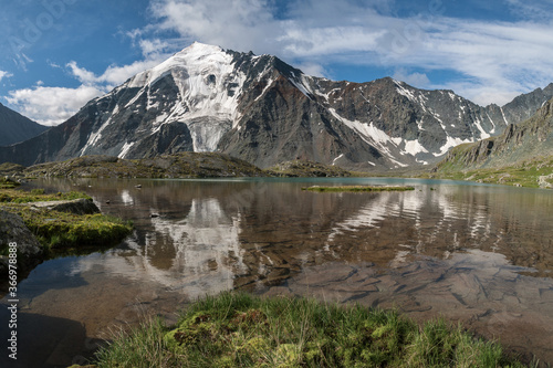 Glacier on a mountain peak. The mystical face of a ghost is reflected in the lake. Altai  Russia.