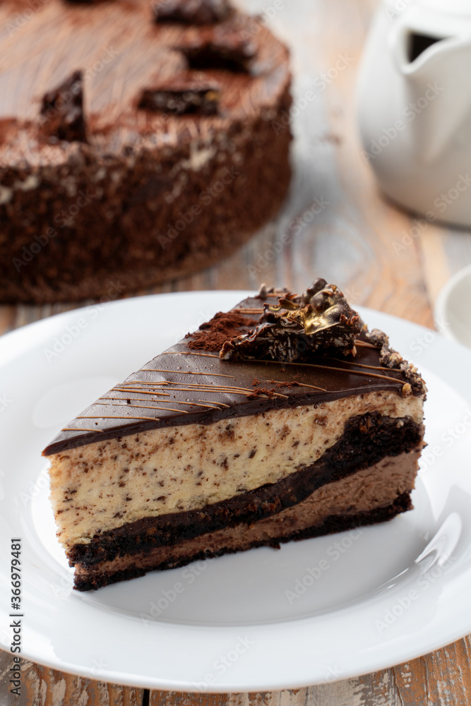 A slice of classic chocolate birthday torte on a wooden table with a cup of black tea A slice of classic chocolate birthday torte on a wooden table with a cup of black tea
