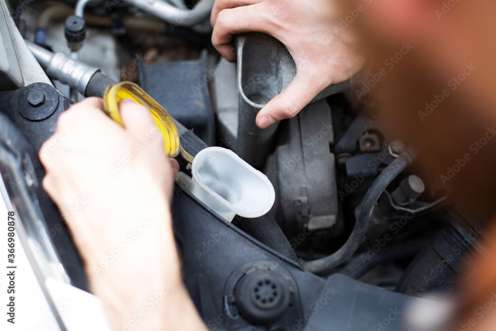 Checking and refilling fluid levels in the car. Vehicle check-up. Under the hood of a car view. Checking and refilling fluid levels in the car. Vehicle check-up. Under the hood of a car view.