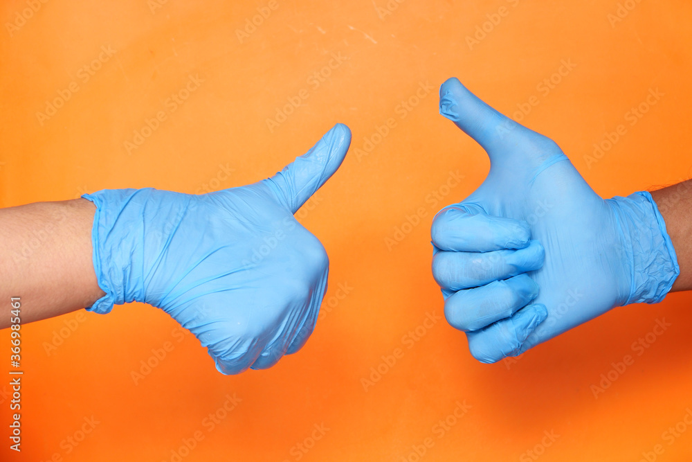 Close-up of a tow people hand in medical gloves showing a thumb-up. Close-up of a tow people hand in medical gloves showing a thumb-up.