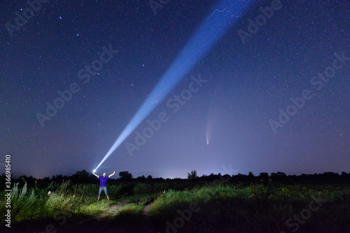 Man with flashlight and starry sky with comet