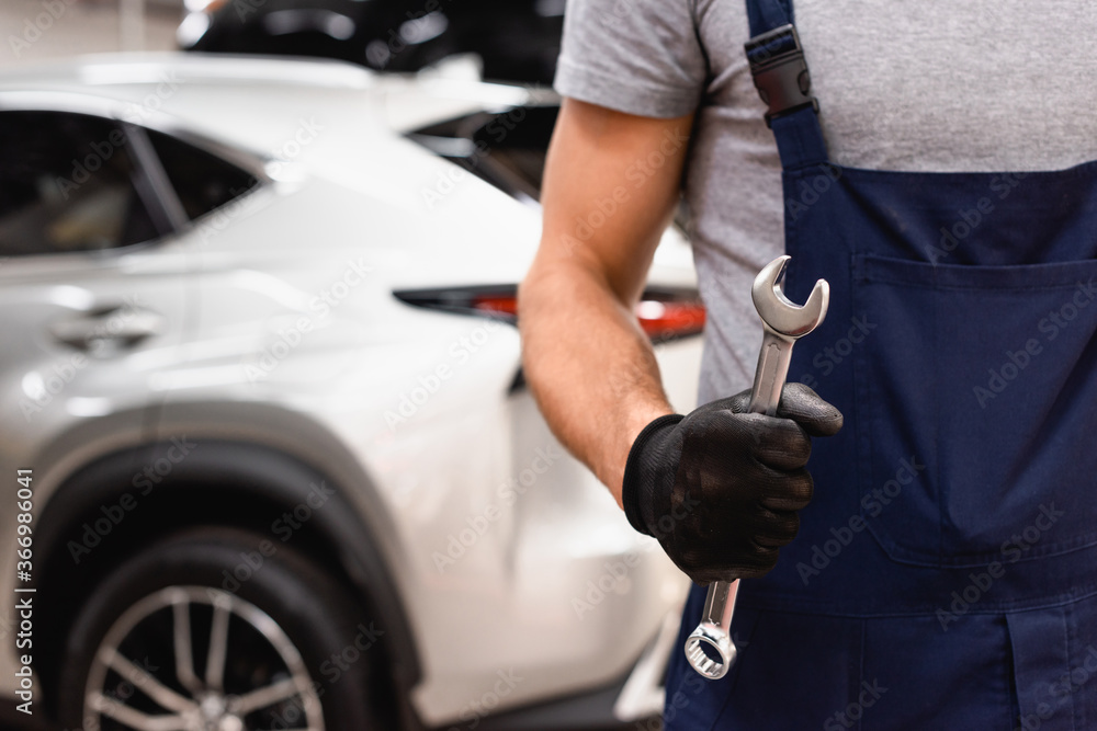 cropped view of mechanic in latex glove holding wrench cropped view of mechanic in latex glove holding wrench
