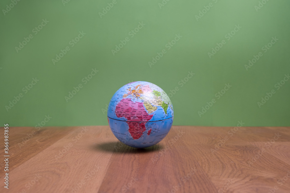 Weltkugel mit Blick auf Afrika, Europa und Asien auf Holztisch mit grünem Hintergrund Weltkugel mit Blick auf Afrika, Europa und Asien auf Holztisch mit grünem Hintergrund