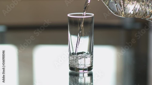 Pure drinking water is poured into a glass cup on a light background photo