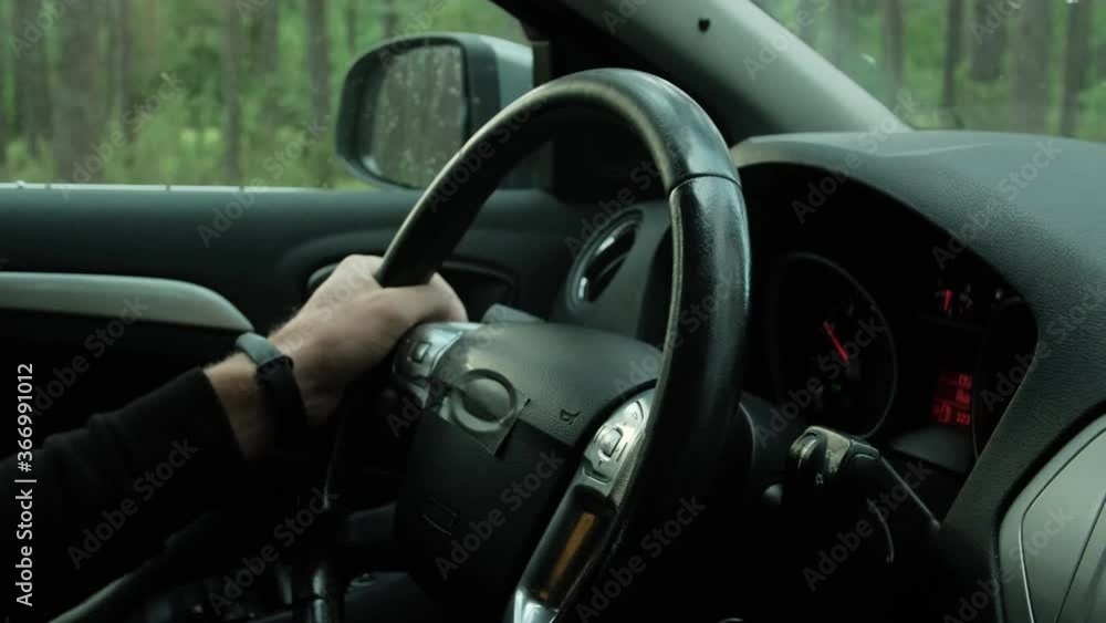 Close up of a man steers a car. Outside the window the forest Close up of a man steers a car. Outside the window the forest