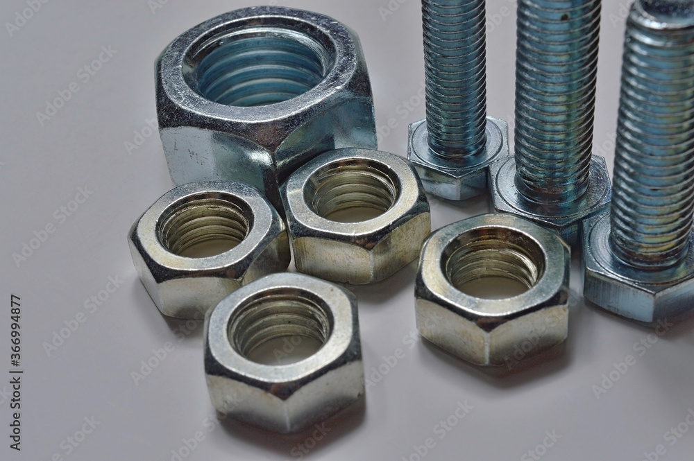 bolts and nuts of different sizes are laid out on a light background. bolts and nuts of different sizes are laid out on a light background.