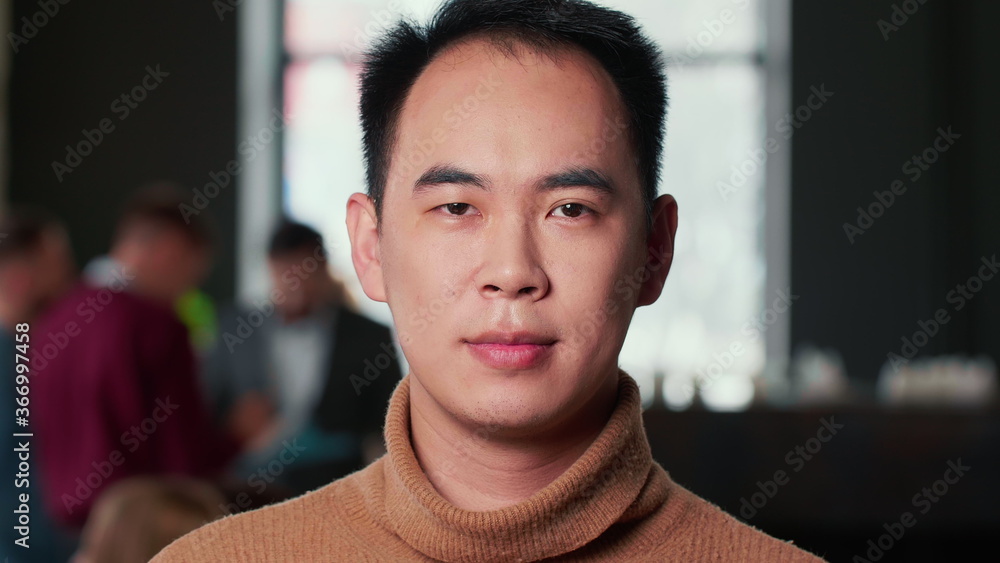 Close-up portrait of young happy Asian entrepreneur businessman looking at camera smiling at modern trendy loft office. Close-up portrait of young happy Asian entrepreneur businessman looking at camera smiling at modern trendy loft office.