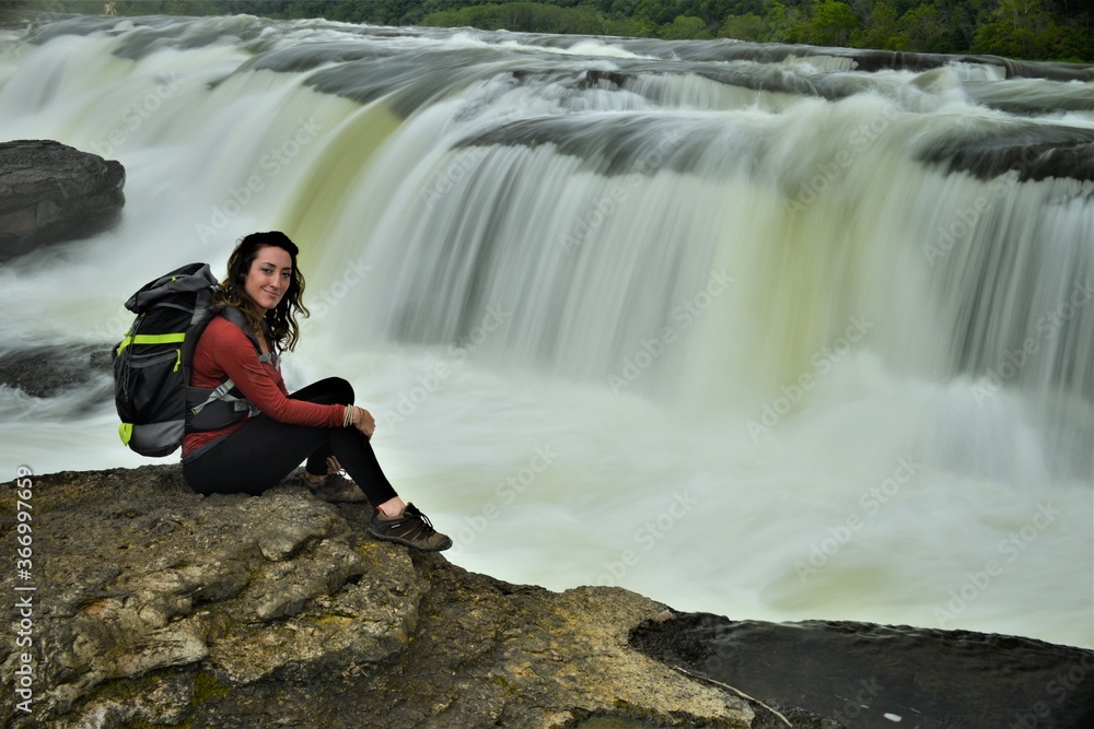 Women Traveling Posing with Backpack beside Waterfall
