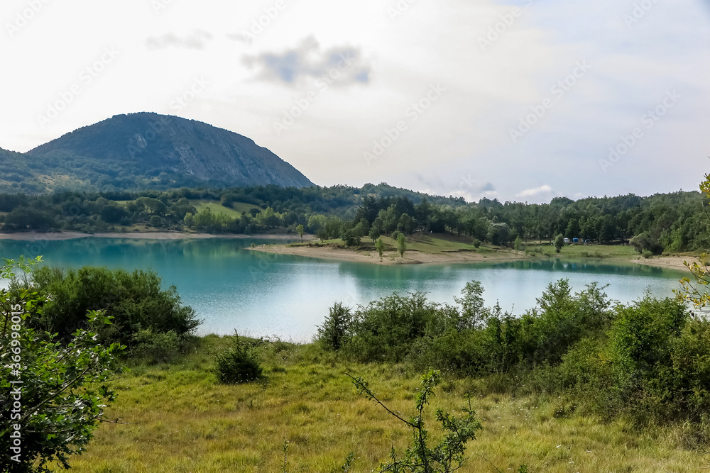 Lake Castel San Vincenzo, dam, with a lot of vegetation and rocky mountain in the background, Castel San Vincenzo commune, Molise region, Isernia province, Italy