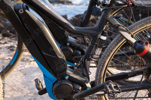 Close up of the motor and battery of two black e bikes. Outdoor activity with bicycle for healty lifestyle. Blue sea on background