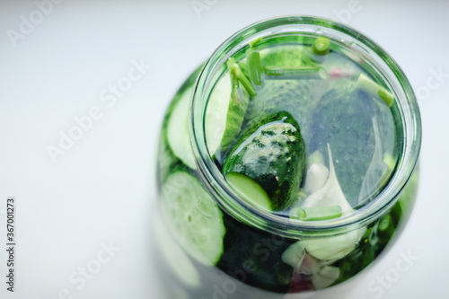 Liter glass jar with lightly salted cucumbers on a white windowsill