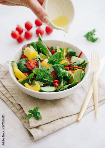 Vegetable salad with olive oil in white bowl on linen napkin