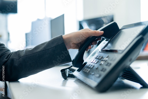 фотографія Closeup female hand on landline phone in office