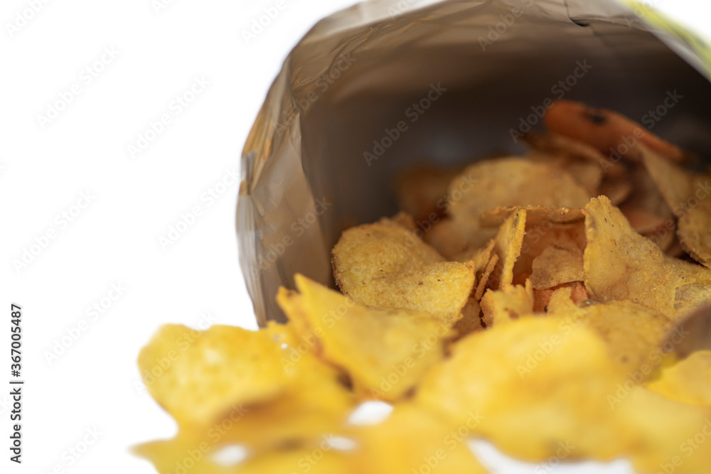 Potato chips poured from a bag lie on a white background. Macro shot