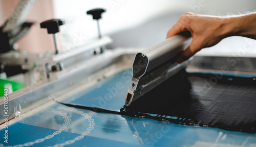 Fotografia Cropped view of man holding squeegee while working with plastisol ink on screen