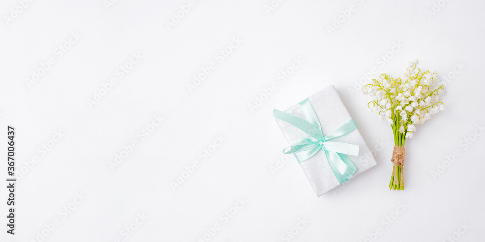 Flat lay festive composition with white flowers and a gift box on a white background