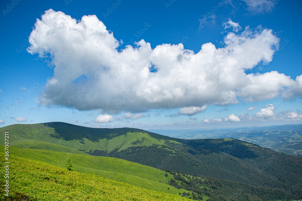 Dramatic white clouds on blue sky over green Carpathian mountains. Tops of the Carpathian mountains. Beautiful landscape with greenery and clouds. Beauty nature landscape. Mountains against the sunny 