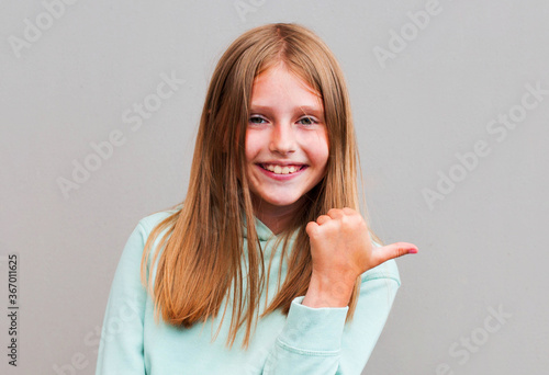 Portrait of positive cheerful girl promoter indicate ads promo direct way point thumb finger copyspace wear good look clothes isolated over grey background