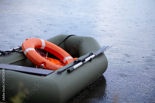 inflatable lifeboat with a lifebuoy on Board floats in the lake during the rain