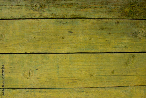 Old tumbledown weathered wood boards background with cracks, yellow painted, shabby rustic barn timbered siding aged withered faded flooring surface. Obsolete blank abstract rustic rundown wall.