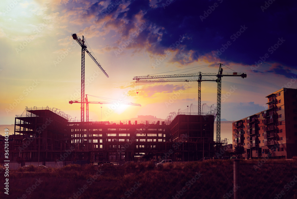 Cranes and building construction.Construction and real estate industry. Sunset and foundation structure of houses.