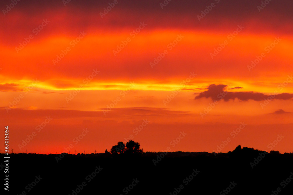 A fiery sunset with a wind farm in the background