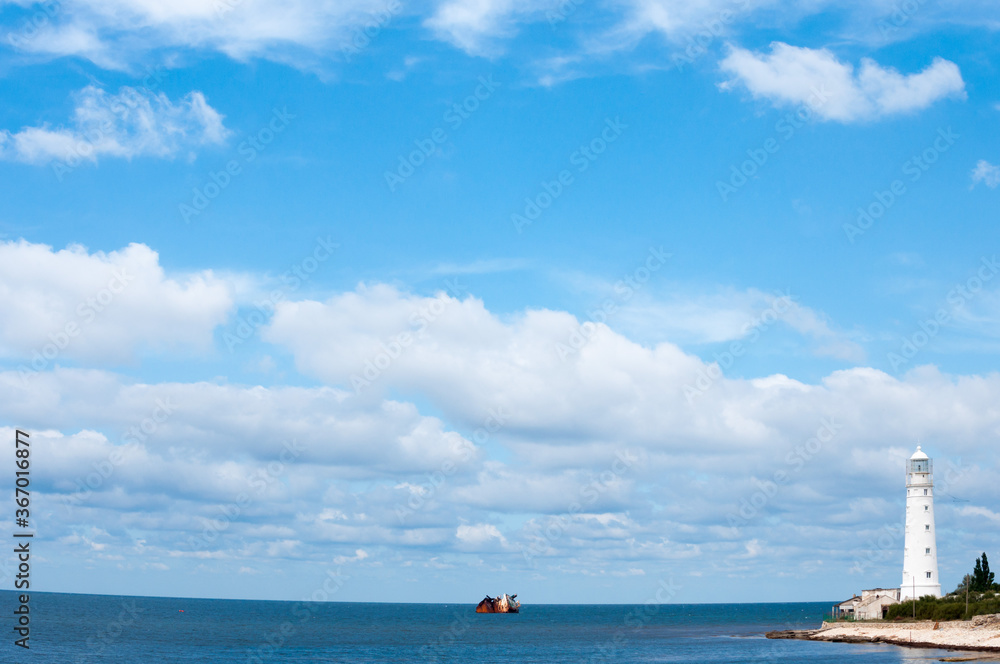 Lighthouse and sunken ship in sunshine day.