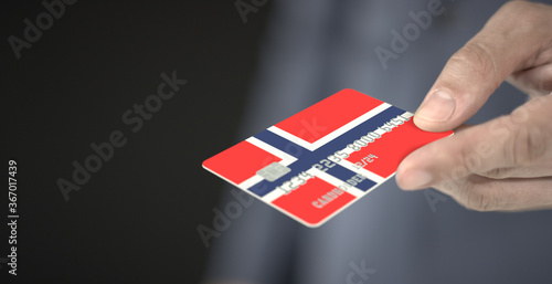 Man gives plastic bank card with printed flag of Norway. Fictional numbers