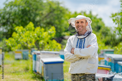 The beekeeper stands crosshands near apiary. Apiculture. Apiary. photo