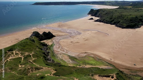 Aerial view of green foliage, large cliffs and a huge sandy beach at low tide (3 Cliffs Bay, Gower Peninsula, Wales, UK) photo