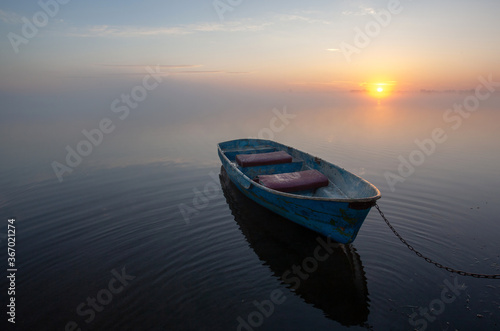 Sunrise on the lake. Lonely old boat on the very shore