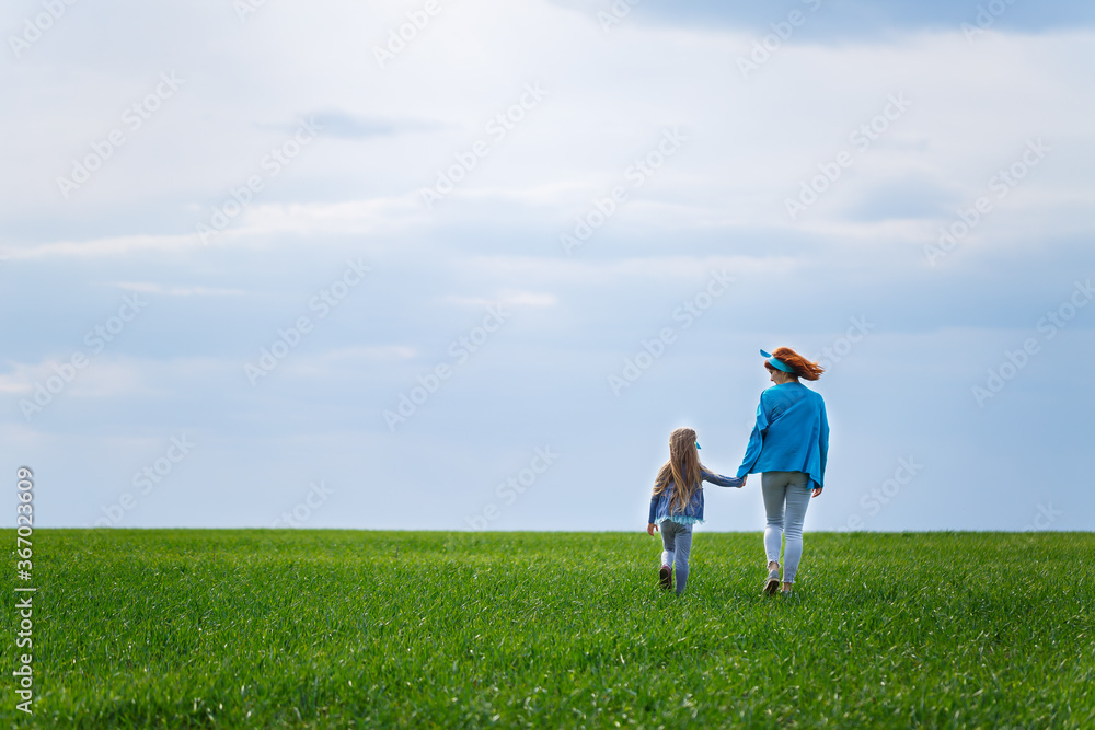 little girl child and mother woman run and jump, green grass in the field, sunny spring weather, smile and joy of the child, blue sky with clouds little girl child and mother woman run and jump, green grass in the field, sunny spring weather, smile and joy of the child, blue sky with clouds