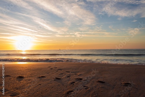 sunrise on the beach with footprints in the sand