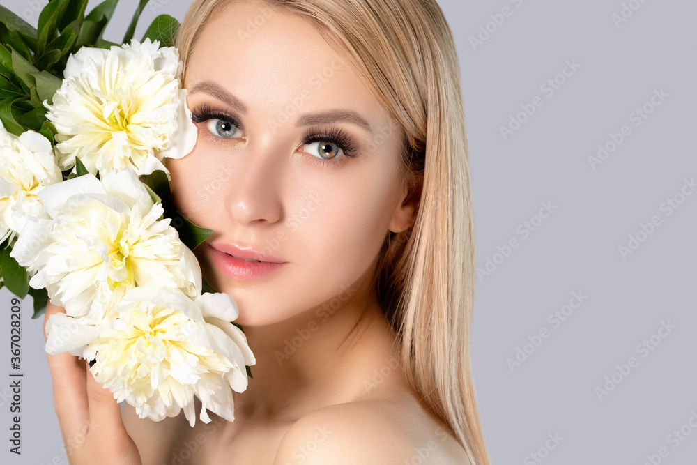 Portrait of a beautiful blonde woman with long hair, beautiful fresh makeup and healthy clean skin with peonies in her hands. Makeup and cosmetology concept. Portrait of a beautiful blonde woman with long hair, beautiful fresh makeup and healthy clean skin with peonies in her hands. Makeup and cosmetology concept.