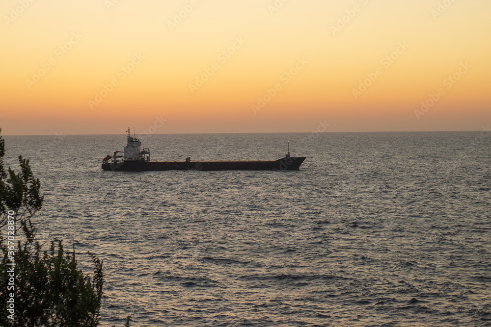 cargo ship going at sunset