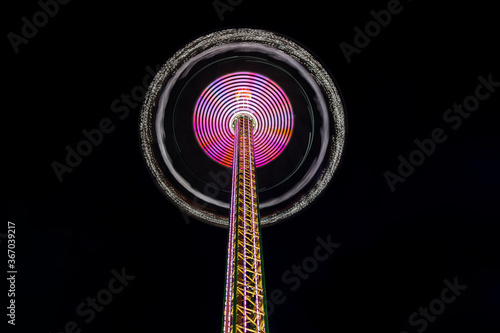 Low angle view of Star flyer, Chain carousel amusement ride, move up and down, and spin around the top of tower with beautiful decorated light on night dark sky background. photo