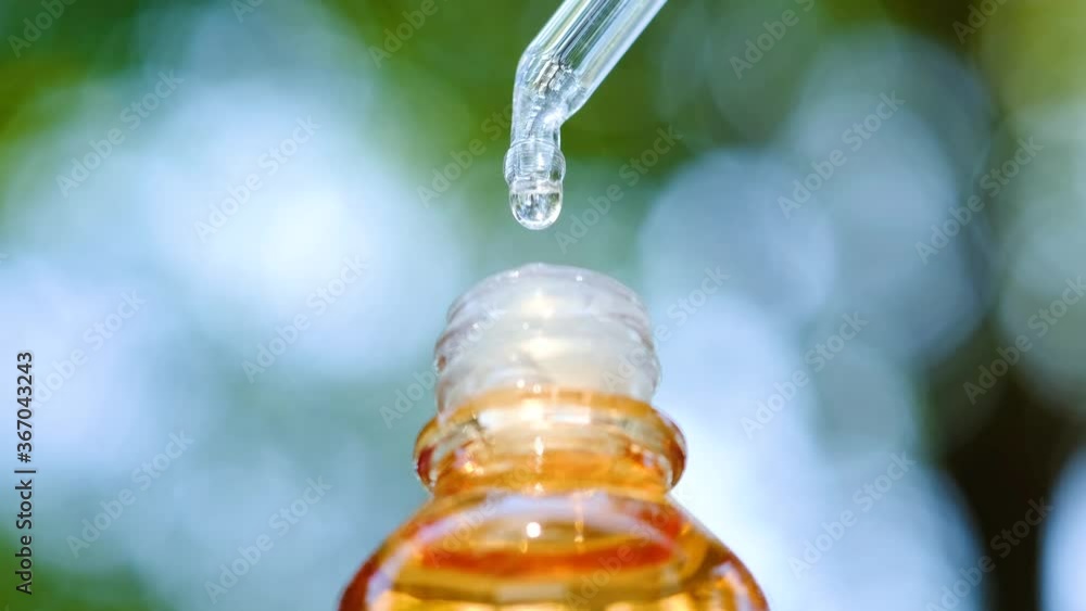 Dropping serum collagen moisturizer of face into clear yellow bottle soft light background. Protector skin Treatment facial essence oil, Vitamin C. Beauty and spa Concept Dropping serum collagen moisturizer of face into clear yellow bottle soft light background. Protector skin Treatment facial essence oil, Vitamin C. Beauty and spa Concept