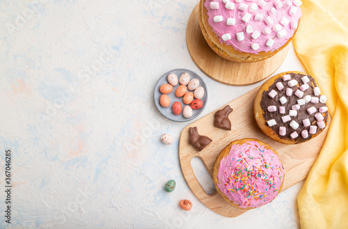 Homemade glazed and decorated easter pies with chocolate eggs and rabbits on a white concrete background. top view, copy space.