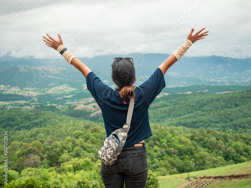Shot from behind, Woman raised arms with mountain view. Happy with nature.