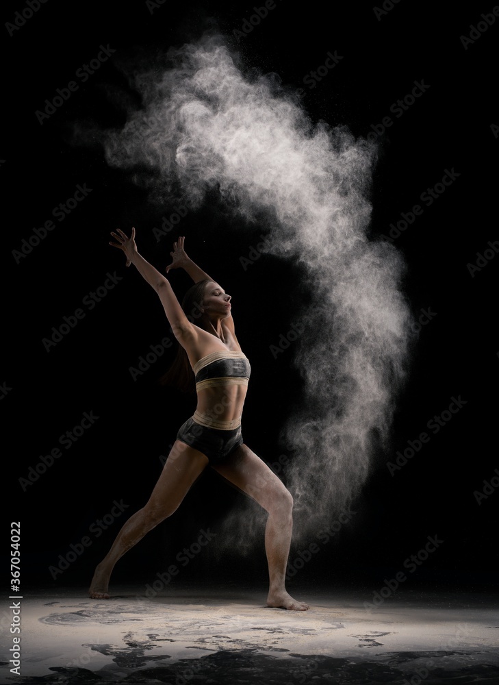 Fototapeta premium Slim female dancer throwing dust in air