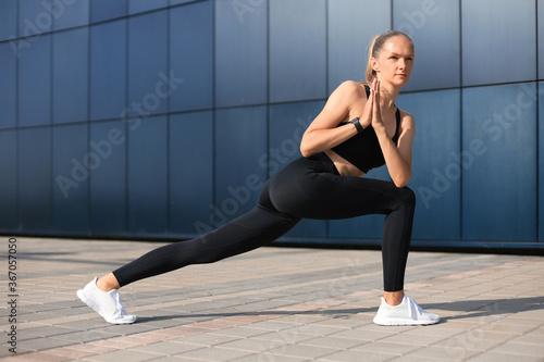 Attractive young fitness woman wearing sports clothing exercising outdoors, stretching exercises.