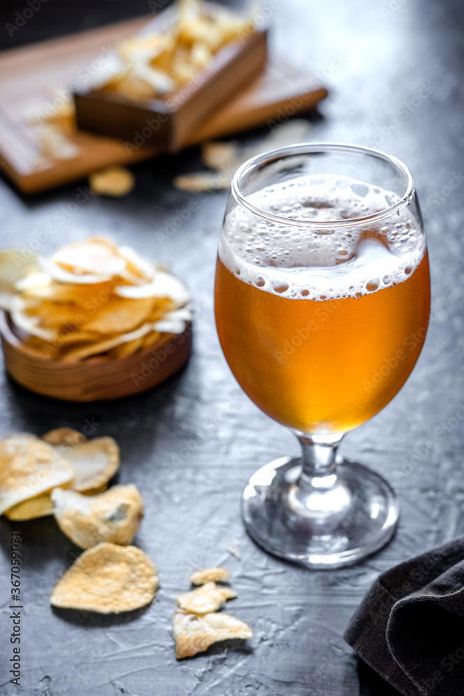 Glass of beer and chips on dark background. Cold beer in a long glass. Glass of beer and chips on dark background. Cold beer in a long glass.