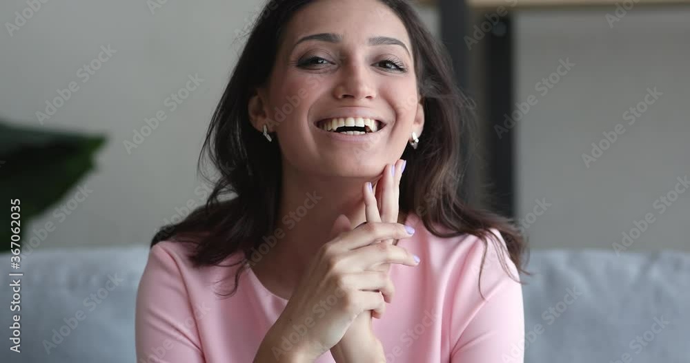 Close up view face of beautiful woman having wide white toothy smile look at camera pose seated on sofa indoor. Natural beauty of indian mixed-race girl, cosmetics procedure fresh perfect skin concept Close up view face of beautiful woman having wide white toothy smile look at camera pose seated on sofa indoor. Natural beauty of indian mixed-race girl, cosmetics procedure fresh perfect skin concept