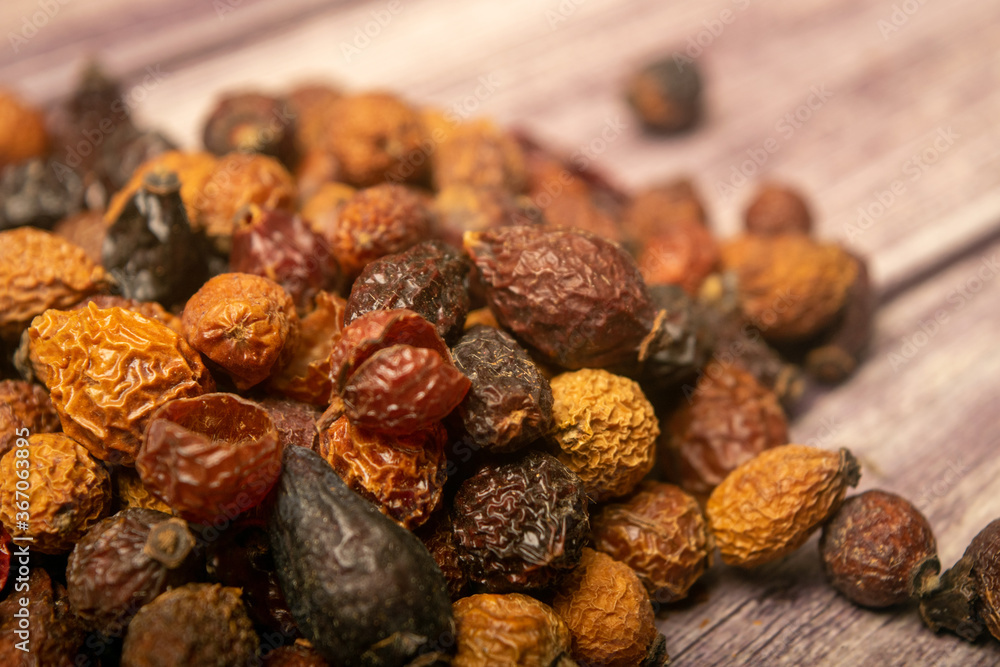 Dried rosehip fruits scattered on a wooden background. Close up. Dried rosehip fruits scattered on a wooden background. Close up.